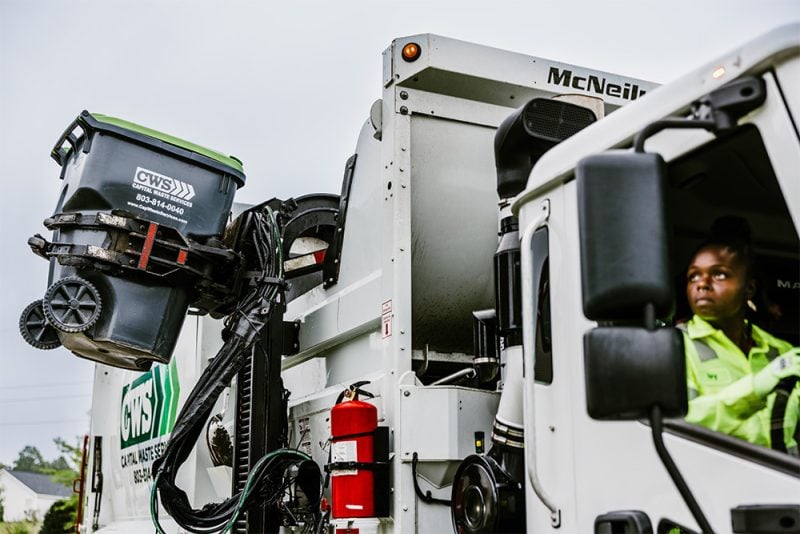 CWS employee driving truck, collecting cans and emptying into truck